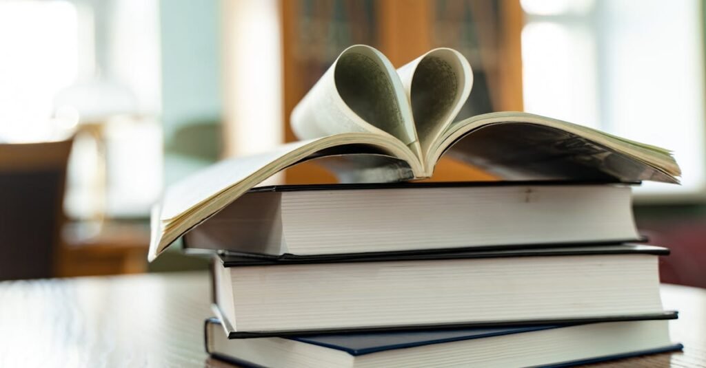 pexels-photo-9490662-9490662 Close-up of stacked books with open pages creating a heart shape, indoors.